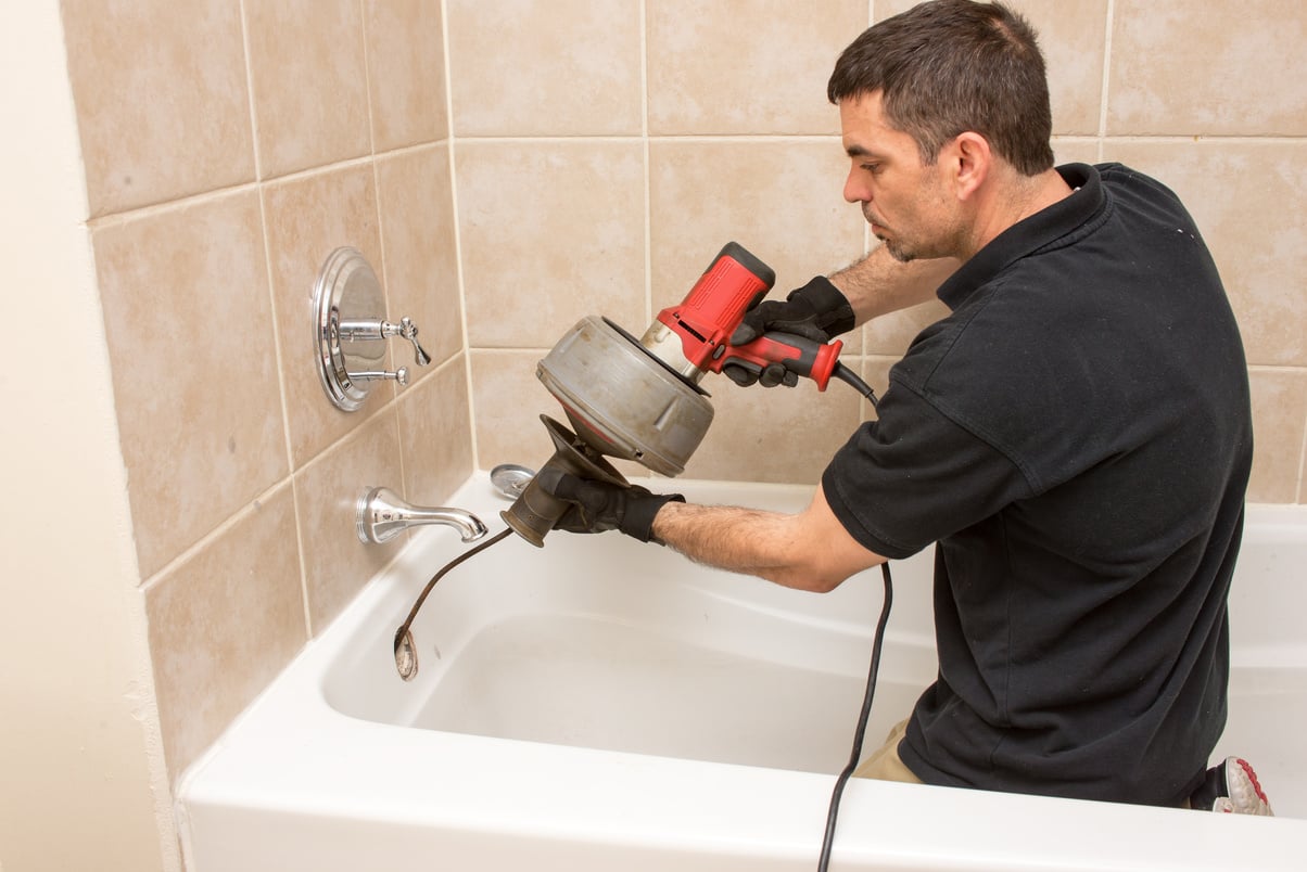 a person using an electric drill to repair a tub